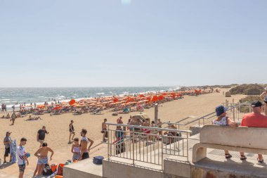 Büyük Kanarya, İspanya, 12 Ekim 2023: birçok insan ve şemsiyeyle bir plaj sahnesi. İnsanlar İspanya 'nın Gran Canaria plajında eğlenirken sahne canlı ve eğlenceli.. 