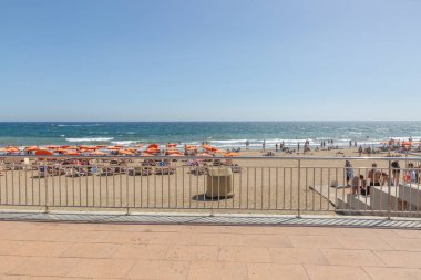 Büyük Kanarya, İspanya, 12 Ekim 2023: birçok insan ve şemsiyeyle bir plaj sahnesi. İnsanlar İspanya 'nın Gran Canaria plajında eğlenirken sahne canlı ve eğlenceli.. 