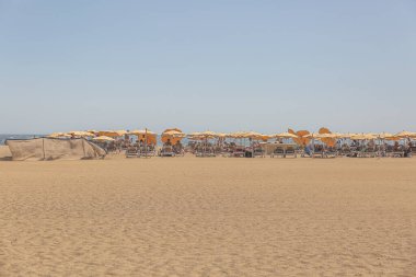 Büyük Kanarya, İspanya, 12 Ekim 2023: birçok insan ve şemsiyeyle bir plaj sahnesi. İnsanlar İspanya 'nın Gran Canaria plajında eğlenirken sahne canlı ve eğlenceli.. 