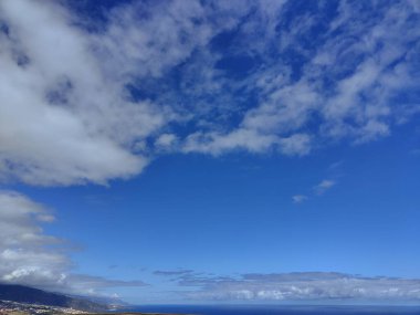 The sky is blue with a few clouds scattered throughout. The clouds are white and fluffy, giving the sky a peaceful and serene appearance