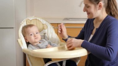 Little baby boy having breakfast sitting in highchair at kitchen. Concept of parenting, healthy nutrition and baby care