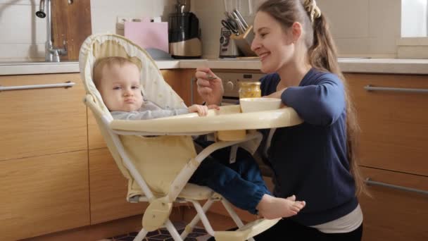 Young Mother Smiling Her Baby Son Sitting Highchair Kitchen Concept — Stock video