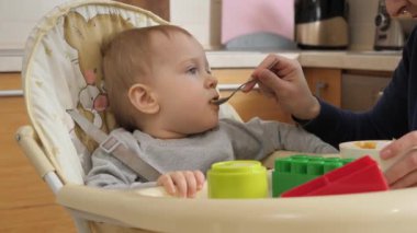 Portrait of happy smiling bbay boy getting messy while eating in highchair. Concept of parenting, healthy nutrition and baby feeding