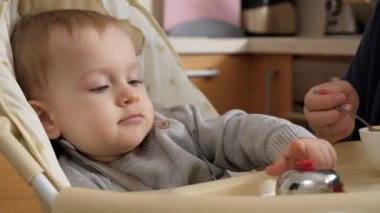 CLoseup of baby boy playing with toys and having fun while eating in highchair. Concept of parenting, healthy nutrition and baby feeding