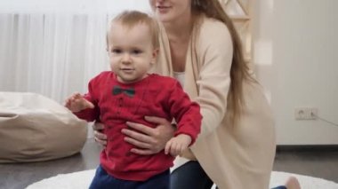 Gülümseyen tatlı çocuk, genç annesiyle yürümeyi öğreniyor. Bebek gelişimi, aile oyunları, ilk adımlar, ebeveynlik ve bakım.