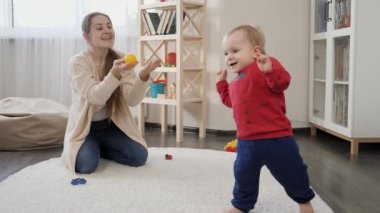 Mutlu anne, küçük oğluna gülerek evde ilk adımlarını atıyor. Bebek gelişimi, aile oyunları, ilk adımlar, ebeveynlik ve bakım.