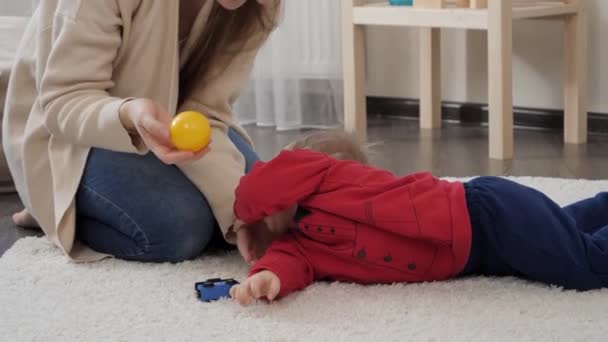幸せな笑顔の女性抱擁し 自宅で床に横たわって彼女の小さな赤ちゃんの息子を保持します 赤ちゃんの発達 家族で遊ぶゲーム 第一歩を踏み出す 親とケア — ストック動画