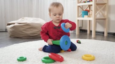 Renkli oyuncak piramit kulesini monte etmeye çalışan sevimli küçük oğlan. Bebek gelişimi, çocuk oyunları, eğitim ve öğrenim