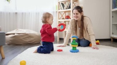 Annesiyle birlikte eğitici oyuncaklarla oynayan ve renkli kule yapmayı öğrenen küçük bir çocuk. Bebek gelişimi, çocuk oyunları, eğitim ve öğrenim