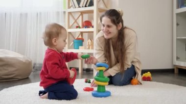 Mutlu gülümseyen anne oyuncak piramit ya da kule monte eden küçük oğluna bakıyor. Bebek gelişimi, çocuk oyunları, eğitim ve öğrenim