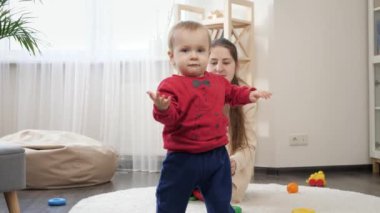 Yakışıklı bebek ilk adımlarını atarken yürümeyi ve gülümsemeyi öğreniyor. Bebek gelişimi, çocuk oyunları, eğitim ve öğrenim