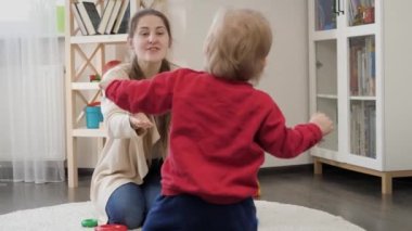 Mutlu gülümseyen anne ilk adımlarını atarken bebeğine yardım ediyor. Bebek gelişimi, çocuk oyunları, eğitim ve öğrenim
