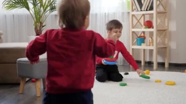 Küçük erkek bebek, ağabeyi ile oturma odasında halının üzerinde oyuncaklarla oynuyor. Çocuk eğitimi kavramı, bebek gelişimi, aile oyunları
