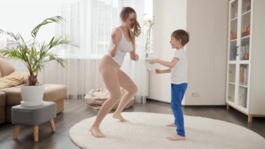 Neşeli çocuk evde annesiyle dans ediyor ve birlikte eğleniyor. Aile birlikte eğleniyor, müzik dinliyor, aktif yaşam tarzı, ebeveynlik ve çocuk gelişimi.