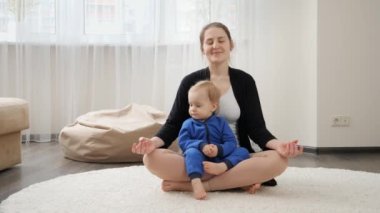 Güzel, genç bir anne ve küçük oğlu yerde oturmuş meditasyon yapıyorlar. Aile sağlığı, aktif yaşam tarzı, ebeveynlik ve çocuk gelişimi