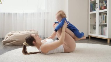Mutlu, gülen çocuk annesiyle yerde spor yaparken eğleniyor. Aile sağlığı, aktif yaşam tarzı, ebeveynlik ve çocuk gelişimi.