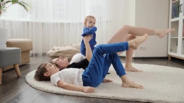 İki çocuk anneleriyle yerde yatıp spor ve spor egzersizleri yapıyor. Aile sağlığı, aktif yaşam tarzı, ebeveynlik ve çocuk gelişimi.