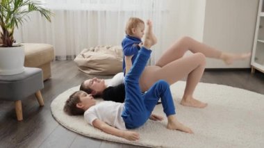 Evde çocukları yerdeyken spor ve spor dersleri alan güzel bir kadın. Aile sağlığı, aktif yaşam tarzı, ebeveynlik ve çocuk gelişimi.