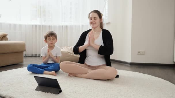Uśmiechnięta Kobieta Synem Ćwicząca Jogę Medytująca Dywanie Domu Rodzinna Opieka — Wideo stockowe