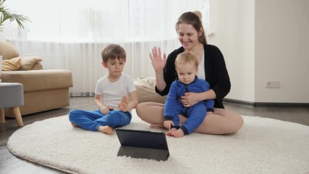 Усміхнена Мати Дивиться Онлайн Урок Йоги Роздумує Своїми Синами Вдома — стокове відео