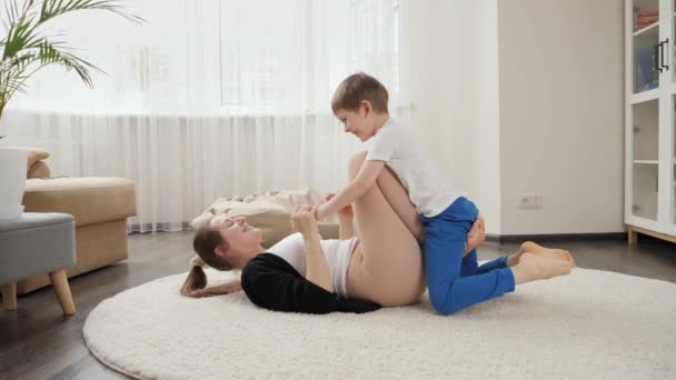 Szczęśliwa Uśmiechnięta Matka Robi Ćwiczenia Fitness Swoim Letnim Synem Dywanie — Wideo stockowe