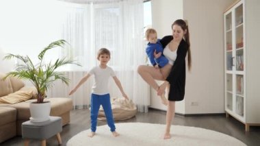 Çocuklu, tek bacaklı ve evde yoga yapan genç bir anne. Aile sağlığı, aktif yaşam tarzı, ebeveynlik ve çocuk gelişimi.