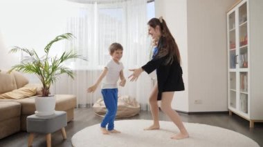 Evde bebeğini kucağında büyük oğluyla dans eden gülümseyen bir kadın. Aile birlikte eğleniyor, müzik dinliyor, aktif yaşam tarzı, ebeveynlik ve çocuk gelişimi.