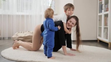 Küçük çocuğun annesine bakıp ağabeyiyle oynayıp eğlendiği komik bir fotoğraf. Aile birlikte eğleniyor, müzik dinliyor, aktif yaşam tarzı, ebeveynlik ve çocuk gelişimi.