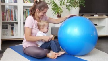 Genç bir anne ve küçük oğlu oturma odasında spor yaparken Fitball oynuyorlar. Sağlık, spor, çocuk bakımı ve çocuk gelişimi kavramı.