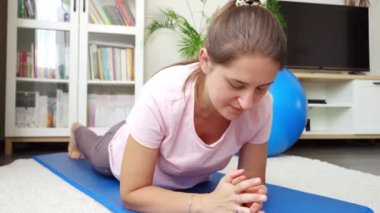 Genç bir kadın fitness antrenmanı sırasında tahta örttükten sonra spor paspasına düşüyor. Evde sağlık, spor ve yoga kavramı