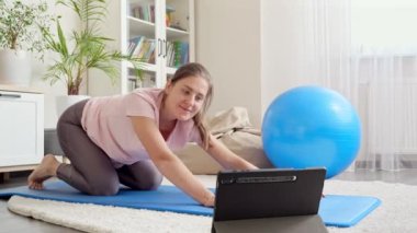 Mutlu gülümseyen kadın tablet bilgisayarda fitness dersi izlerken online spor antrenmanlarına el sallıyor. Evde sağlık, spor ve yoga kavramı