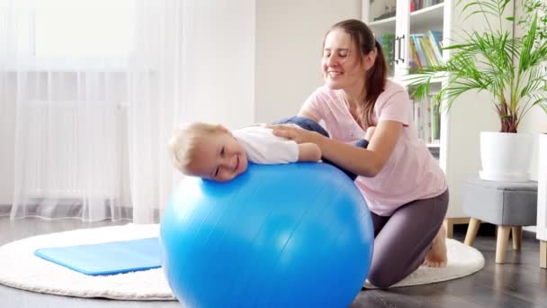 Lächelnde Mutter Und Baby Bei Fitnessübungen Auf Fitball Hause Konzept — Stockvideo