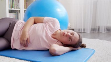 Zor nefes alan terli bir kadın spor paspası üzerinde kalas egzersizi yapmadan önce ara veriyor. Evde sağlık, spor ve yoga kavramı.