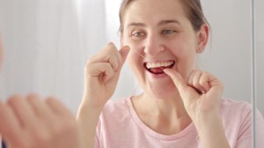 Dişlerini temizlemek için diş ipi kullanan genç bir kadının yakın plan portresi. Diş sağlığı, ağız kontrolü ve ağız temizliği kavramı