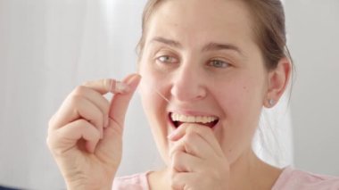 Dişleriyle ilgilenen ve diş ipi kullanan esmer bir kadının yakın çekimi. Diş sağlığı, ağız kontrolü ve ağız temizliği kavramı
