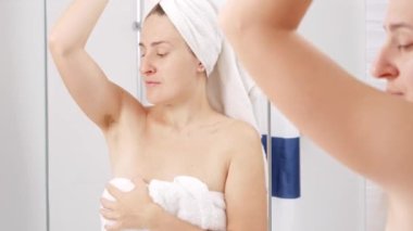 Genç bir kadın kolunu kaldırıyor ve uzun siyah saçlı koltukaltını kokluyor. Hijyen, doğal güzellik, kadınlık ve vücut kıllarının uzaması kavramı