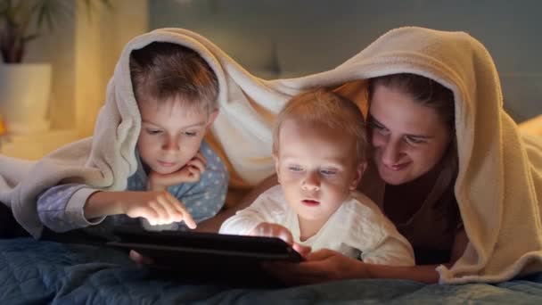Два Хлопчики Піжамі Розважаються Матір Ліжку Грають Ігри Планшетному Комп — стокове відео