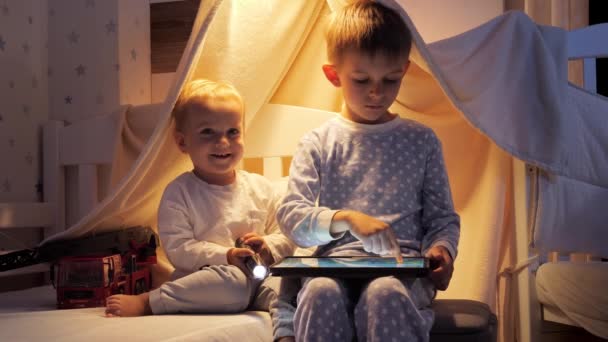Two Cute Boys Pajamas Playing Games Tablet Computer Bed Night — Stock Video