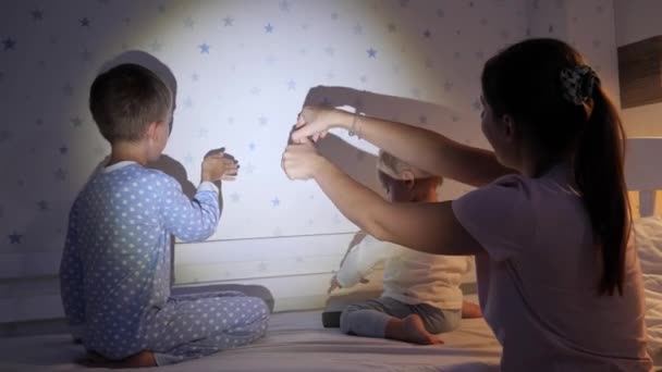 Νεαρή Μητέρα Παιδιά Που Κάνουν Θέατρο Σκιών Στον Τοίχο Της — Αρχείο Βίντεο