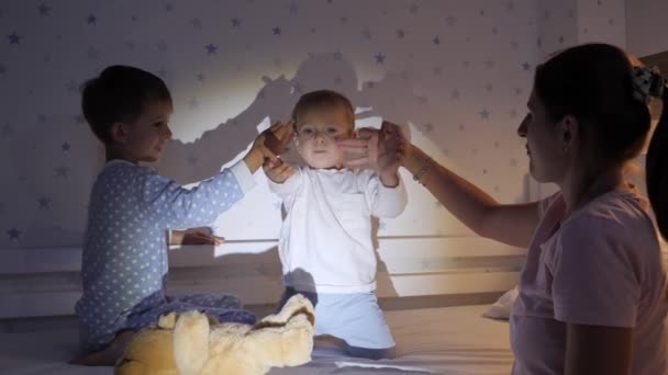 两个穿着睡衣的男孩和一个晚上在卧室里玩手电筒下的影子的妈妈 有时间在一起的家庭 养育子女 快乐的童年和娱乐 — 图库视频影像