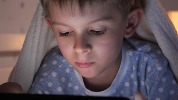 침대에 타블렛 컴퓨터로 아이의 얼굴을 클로즈업합니다 아이들의 비밀을 사용하는 아이들의 — 비디오