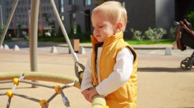 Salıncakta çocuk parkında dikilirken ağlayan üzgün çocuk. Çocuklar dışarıda oynuyor, çocuklar dışarıda, yaz tatili ve tatil.
