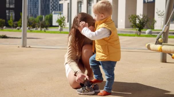 Young Caring Mother Helping Her Baby Son Putting Shoes Playground — Stock Video