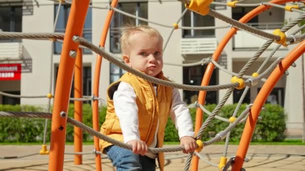 Lindo Bebé Sonriendo Divirtiéndose Subiendo Las Cuerdas Redes Patio Recreo — Vídeos de Stock