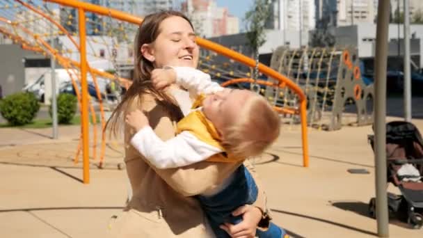 도시의 놀이터에서 아기를 돌게하는 여인의 움직임 밖에서 아이들 밖에서 아이들 — 비디오