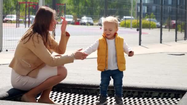 Ung Mamma Hjälper Sin Lille Son Hoppa Studsmatta Lekplatsen Glad — Stockvideo