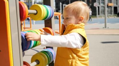 Çocuk parkında renkli abaküsle oynayan küçük bir çocuğun portresi. Çocuk gelişimi, çocuk eğitimi, bebek eğitimi