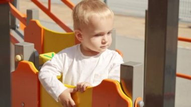 Arka bahçede renkli çocuk parkında yürüyen sevimli bir erkek bebek. Çocuk gelişimi, çocuk eğitimi, bebek eğitimi