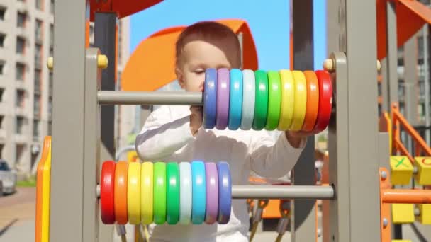 小男孩和五颜六色的算盘在操场上玩耍 儿童发展 儿童教育 婴儿学习 — 图库视频影像