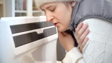 Evinde elektrikli ısıtıcının karşısında üşümüş bir kadının portresi. Enerji krizi, yüksek faturalar, ekonomi ve aylık kamu hizmetleri ödemelerinde tasarruf kavramı